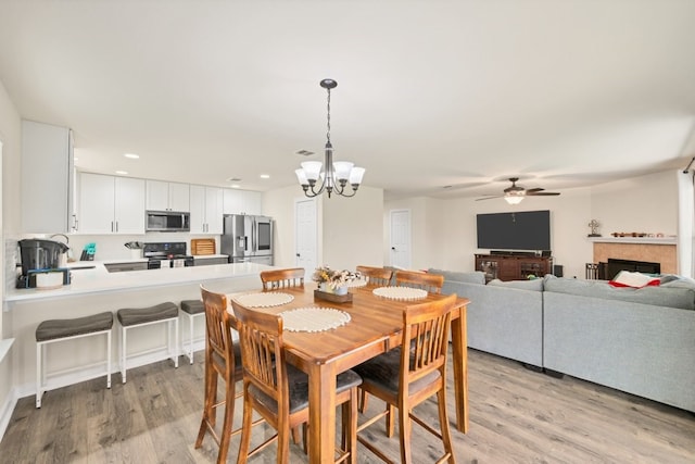 360 Gina Dr, Kyle, TX 78640 - dining space featuring light wood-style floors, ceiling fan, a chandelier, and recessed lighting