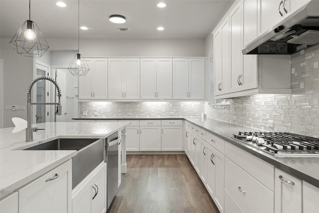 kitchen with pendant lighting, dark hardwood / wood-style floors, light stone countertops, white cabinetry, and stainless steel appliances