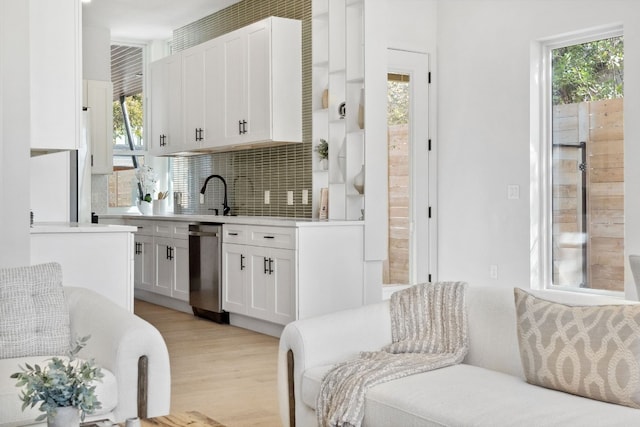 kitchen featuring white cabinets, light hardwood / wood-style floors, tasteful backsplash, and a healthy amount of sunlight