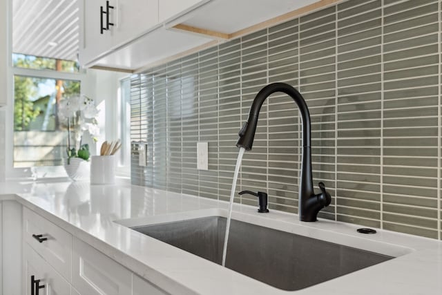 kitchen featuring white cabinets, decorative backsplash, and sink