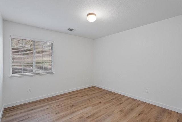 spare room with a textured ceiling and light hardwood / wood-style floors