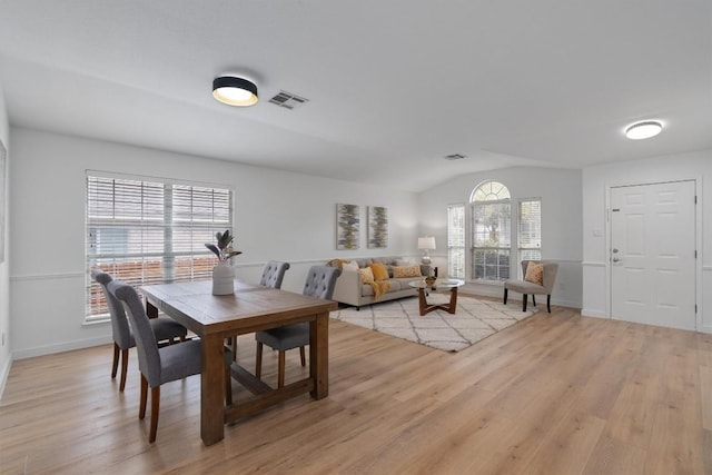 dining room with vaulted ceiling and light wood-type flooring