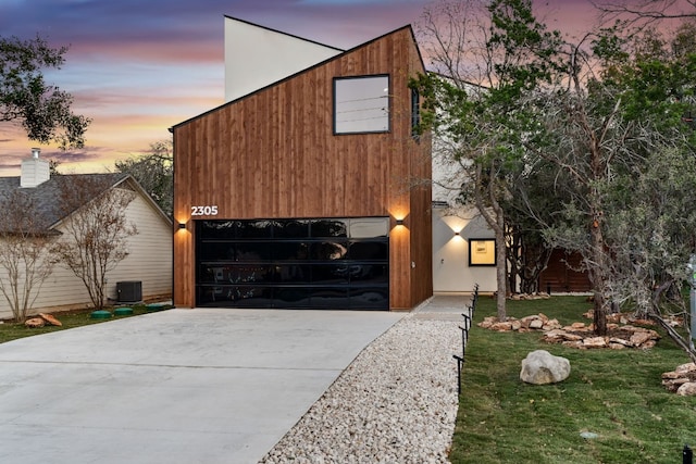 modern home with a garage, central AC unit, and a lawn