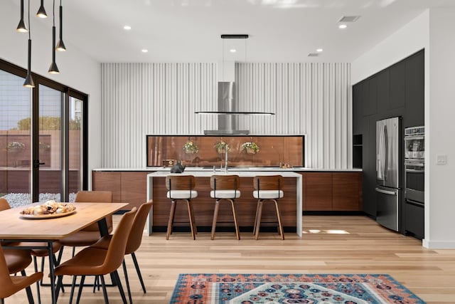 kitchen featuring appliances with stainless steel finishes, a center island, decorative light fixtures, and light hardwood / wood-style floors