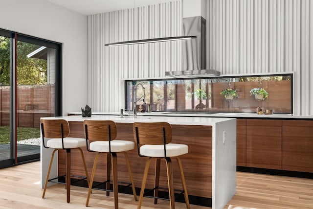 bar featuring wall chimney exhaust hood, light hardwood / wood-style floors, and sink