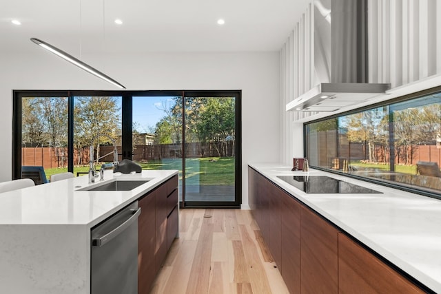 kitchen featuring sink, wall chimney range hood, stainless steel dishwasher, light hardwood / wood-style floors, and black electric stovetop