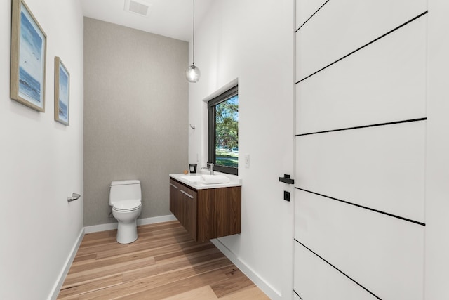 bathroom with hardwood / wood-style floors, vanity, and toilet