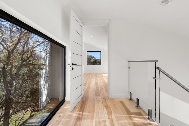 hallway with lofted ceiling and light hardwood / wood-style flooring