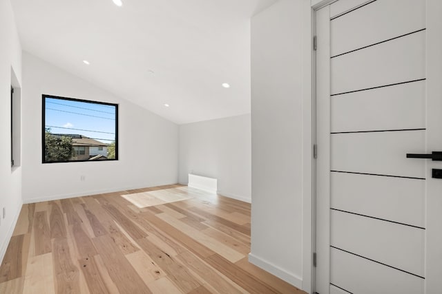 additional living space featuring vaulted ceiling and light hardwood / wood-style flooring