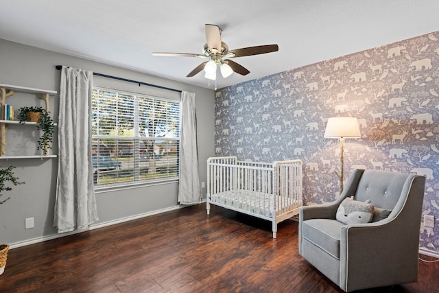 bedroom featuring ceiling fan, dark hardwood / wood-style floors, and a crib