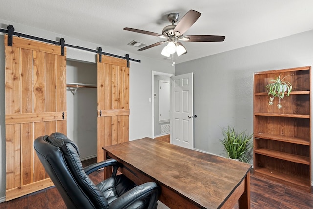 office area with dark hardwood / wood-style floors, a barn door, and ceiling fan