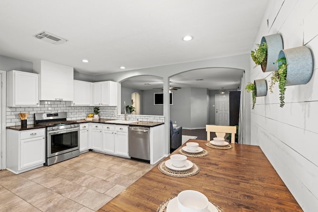 kitchen with backsplash, stainless steel appliances, ceiling fan, sink, and white cabinets