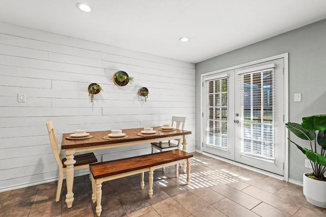 dining area with wooden walls and french doors