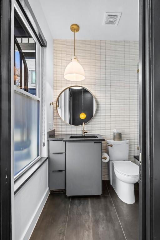 bathroom with vanity, toilet, tile walls, and concrete floors