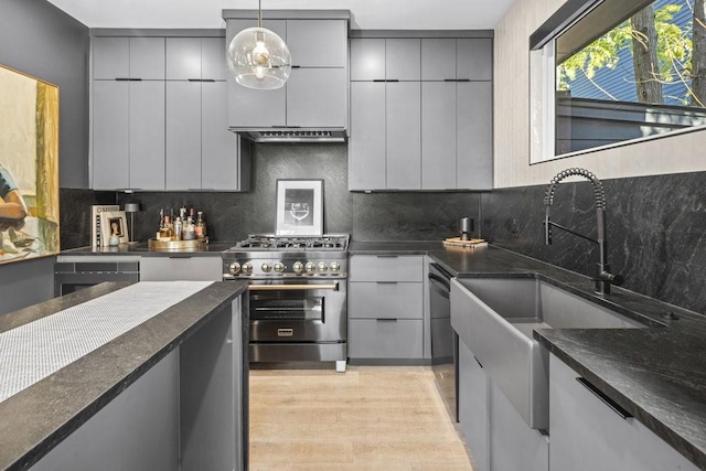 kitchen with decorative light fixtures, gray cabinets, decorative backsplash, and high end range