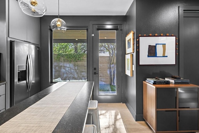 kitchen with decorative light fixtures, stainless steel refrigerator with ice dispenser, and light hardwood / wood-style flooring