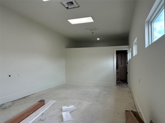 empty room with plenty of natural light, baseboards, and concrete flooring