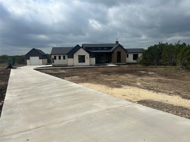 modern inspired farmhouse with a garage, an outbuilding, and driveway