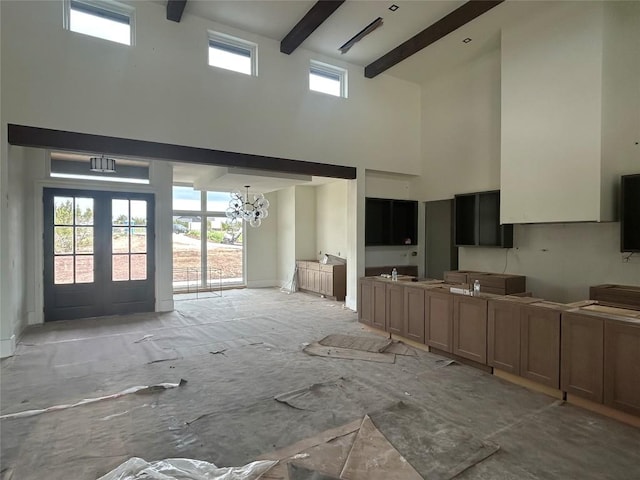 interior space with beamed ceiling, open floor plan, a chandelier, and a towering ceiling
