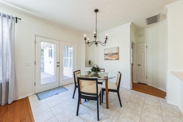 dining area with a chandelier, ornamental molding, french doors, and light hardwood / wood-style flooring