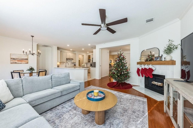 living room featuring sink, ceiling fan with notable chandelier, crown molding, and dark wood-type flooring