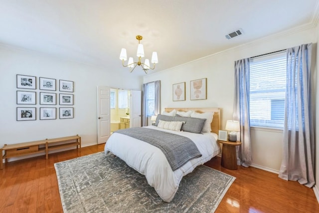 bedroom featuring ensuite bath, wood-type flooring, multiple windows, and a notable chandelier