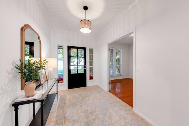 entryway with light wood-type flooring and crown molding