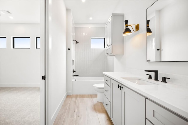 full bathroom with toilet, tiled shower / bath, hardwood / wood-style floors, and vanity