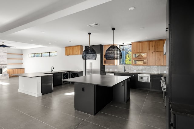 kitchen featuring ceiling fan, pendant lighting, a center island, decorative backsplash, and sink