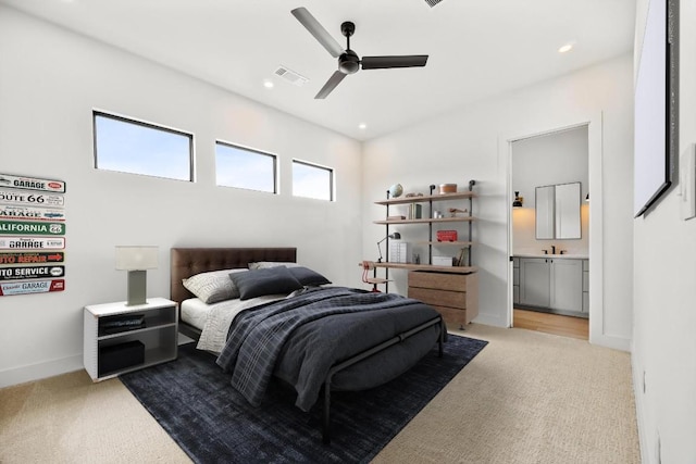 bedroom featuring ceiling fan, light colored carpet, sink, and ensuite bathroom