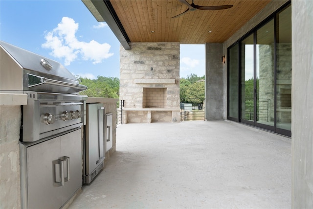 view of patio / terrace with ceiling fan, an outdoor stone fireplace, and an outdoor kitchen