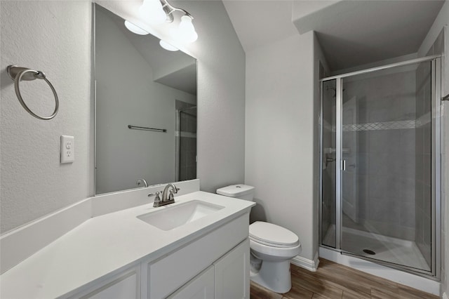 bathroom with hardwood / wood-style floors, vanity, a shower with door, and toilet