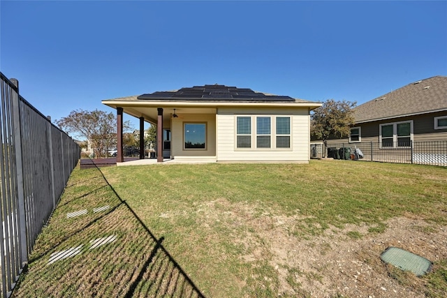 back of house featuring ceiling fan, a yard, a patio, and solar panels