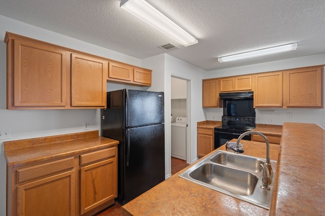 kitchen with a textured ceiling, sink, washer and dryer, and black appliances