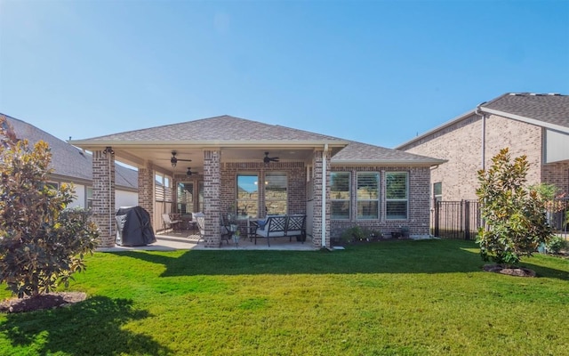 rear view of property with ceiling fan, a patio, and a lawn