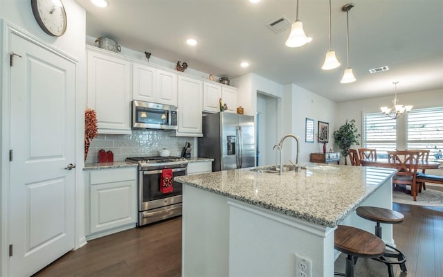 kitchen featuring white cabinetry, light stone counters, an island with sink, and appliances with stainless steel finishes