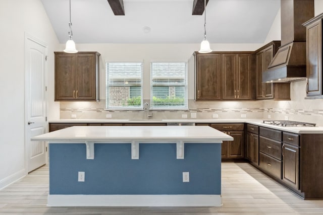 kitchen with premium range hood, light hardwood / wood-style flooring, hanging light fixtures, and lofted ceiling