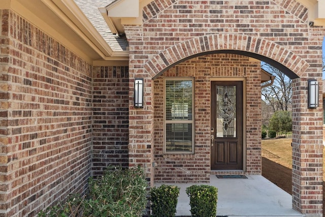 property entrance with brick siding and roof with shingles