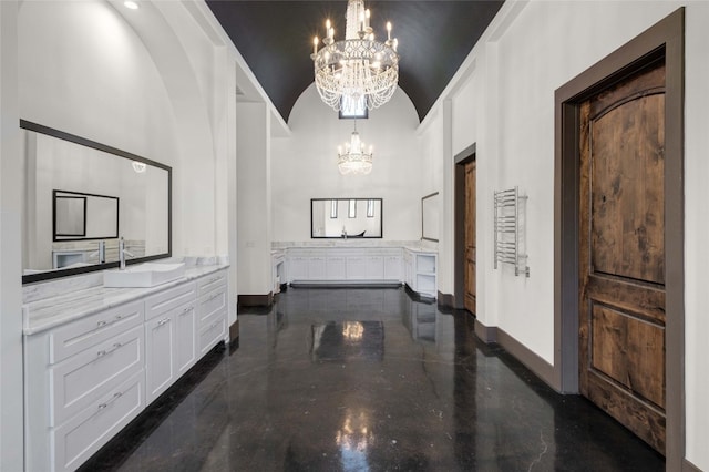 hallway featuring high vaulted ceiling, a notable chandelier, and sink