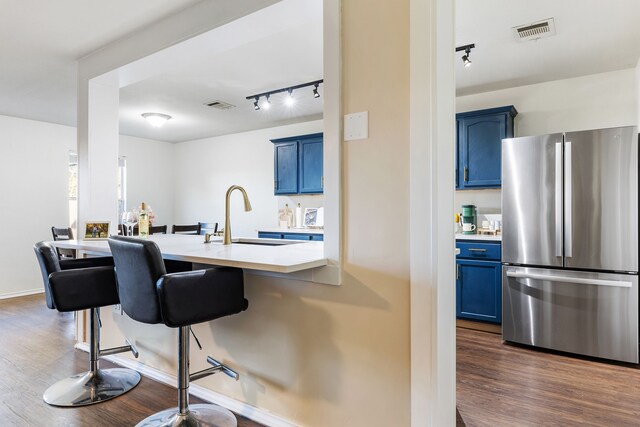 kitchen with sink, stainless steel fridge, a breakfast bar area, and blue cabinets