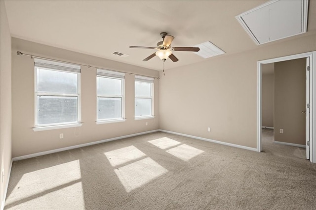 empty room featuring light carpet, a ceiling fan, baseboards, visible vents, and attic access