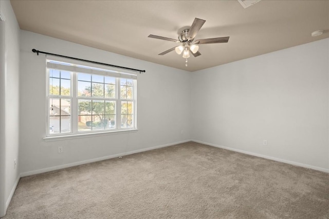 carpeted spare room featuring baseboards and a ceiling fan