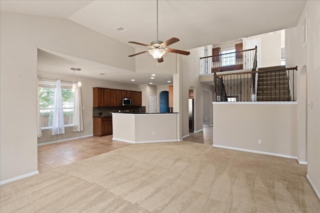 unfurnished living room with light carpet, high vaulted ceiling, and ceiling fan