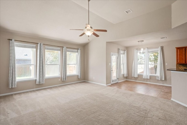 unfurnished living room with light colored carpet, vaulted ceiling, and plenty of natural light