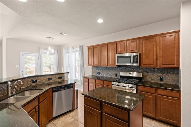 kitchen featuring sink, dark stone counters, a textured ceiling, and appliances with stainless steel finishes