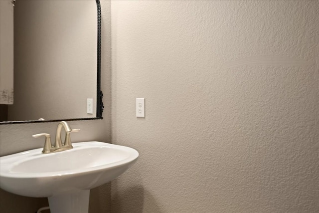 bathroom featuring a sink and a textured wall