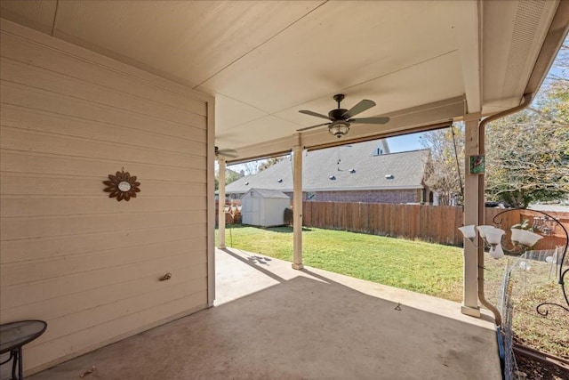 view of patio featuring a storage shed, a fenced backyard, a ceiling fan, and an outbuilding