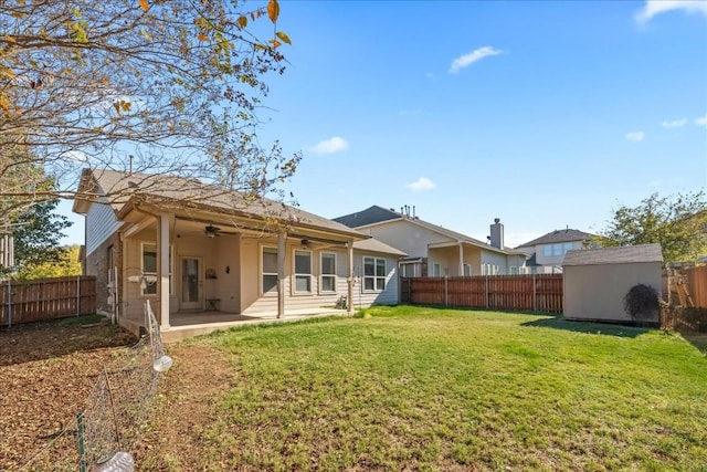 rear view of property with a yard, a patio, a storage shed, ceiling fan, and a fenced backyard