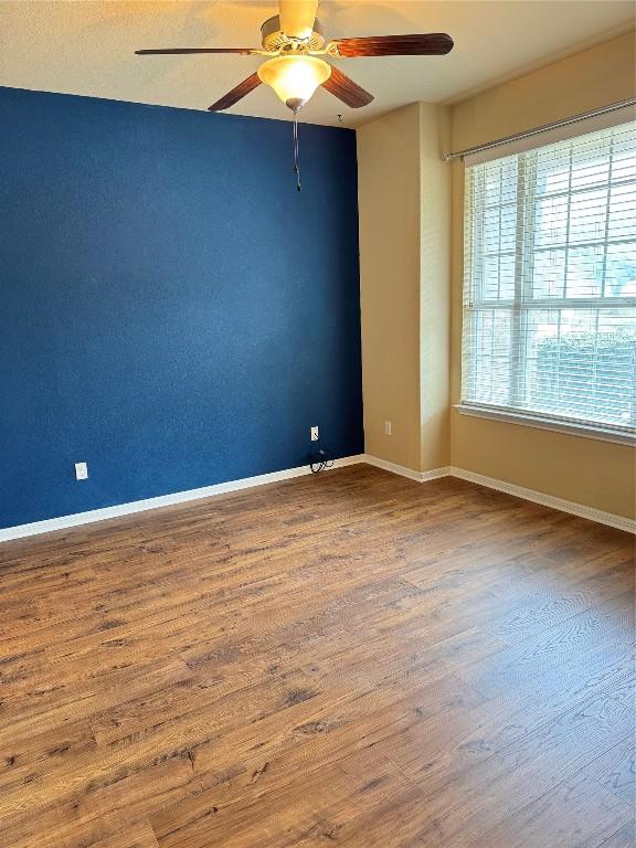 empty room with a ceiling fan, baseboards, and wood finished floors