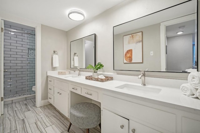 bathroom featuring tiled shower, vanity, and toilet